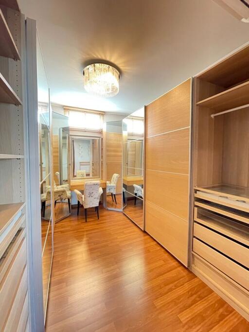 Spacious walk-in closet with wooden flooring and seating area