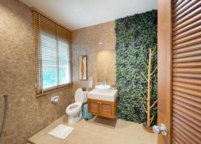 Modern bathroom with a wall-mounted sink, decorative green wall, and natural light