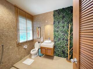 Modern bathroom with a wall-mounted sink, decorative green wall, and natural light