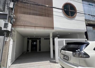 Front view of a modern two-story building with a car parked in the driveway