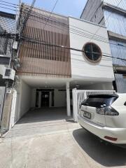 Front view of a modern two-story building with a car parked in the driveway