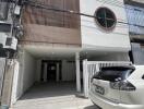 Front view of a modern two-story building with a car parked in the driveway