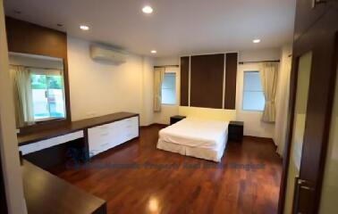 Spacious bedroom with wooden flooring and white furniture