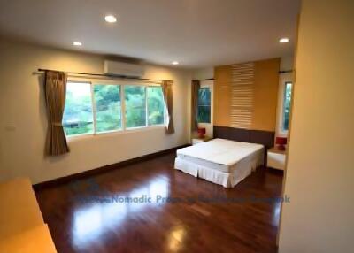 Spacious bedroom with wooden flooring and large windows