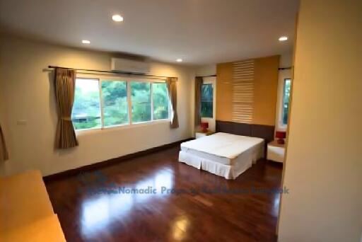 Spacious bedroom with wooden flooring and large windows