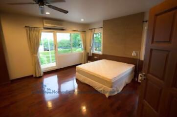 Spacious bedroom with large windows, a ceiling fan, and hardwood floors.