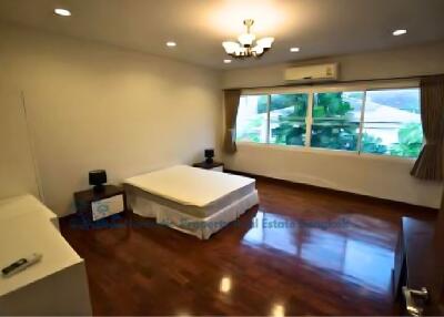 Spacious bedroom with wooden flooring, large window, and modern lighting