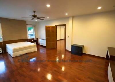 Spacious bedroom with wooden flooring, bed, ceiling fan, and ample natural lighting