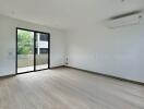 Spacious empty living room with large sliding glass door and balcony view