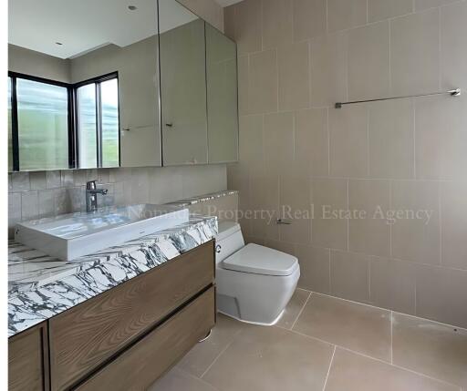 Modern bathroom interior with a large mirror, vanity with marble countertop, and a toilet.