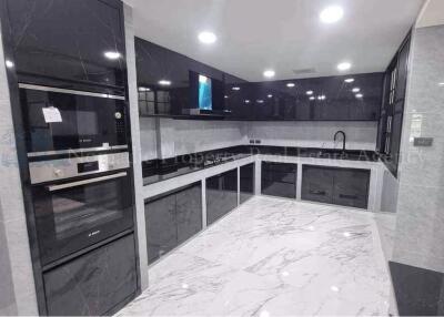 Modern kitchen with black cabinets and marble flooring