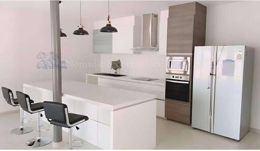 Modern kitchen with island, stainless steel appliances, and barstool seating