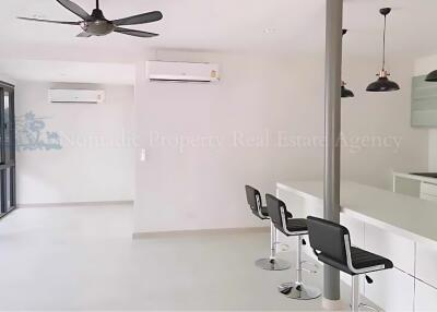 Modern kitchen and dining area with bar stools and ceiling fan