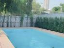 Outdoor swimming pool with wooden deck and surrounding greenery