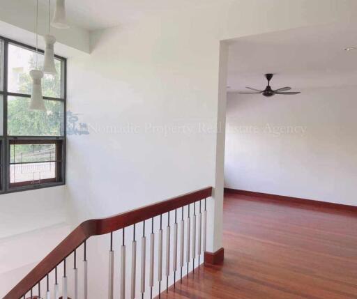 Staircase with wooden railing and spacious living area