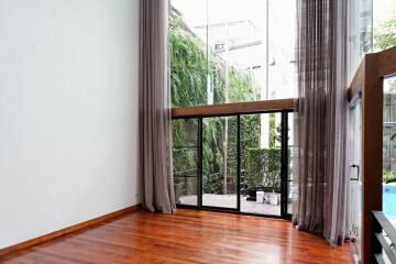 Spacious living room with large floor-to-ceiling windows and wooden flooring