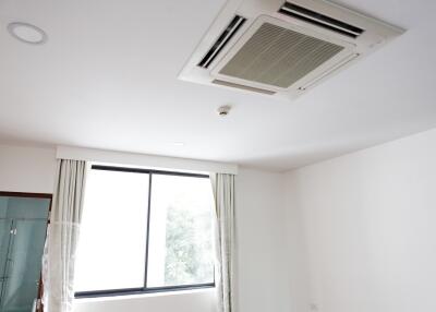 Room with ceiling-mounted air conditioning unit and a large window