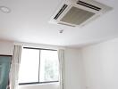 Room with ceiling-mounted air conditioning unit and a large window