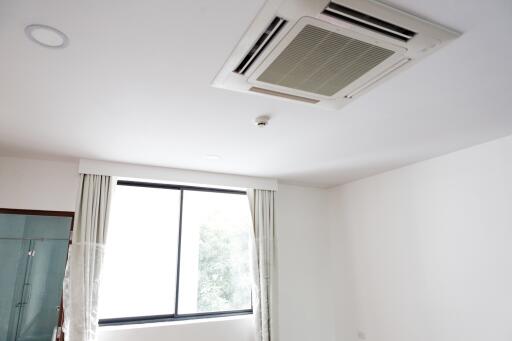 Room with ceiling-mounted air conditioning unit and a large window