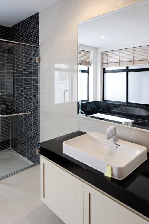 A modern bathroom with a glass shower and a large mirror