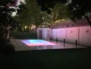 Night view of the backyard with a lit swimming pool