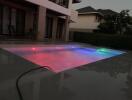 Outdoor pool area with colorful pool lights at dusk