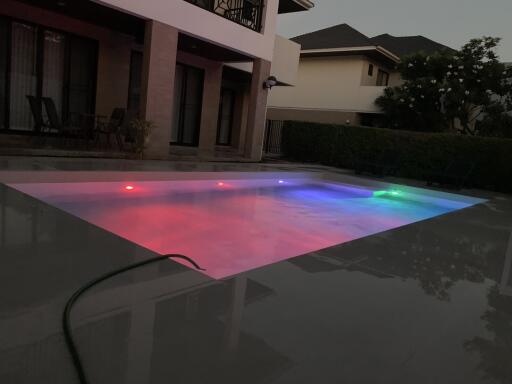 Outdoor pool area with colorful pool lights at dusk