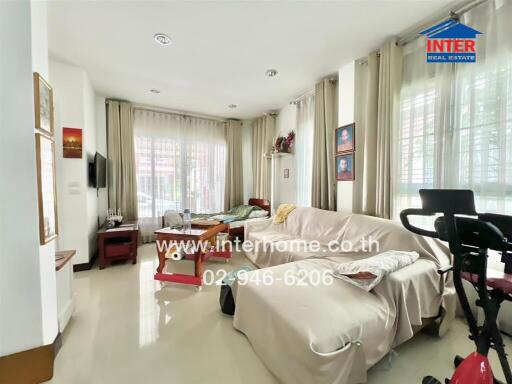 Spacious and well-lit living room with large windows and comfortable seating