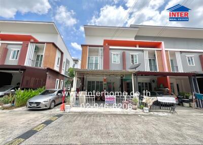 Modern townhouse front view with parked cars and clear sky