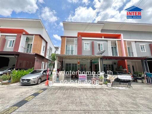 Modern townhouse front view with parked cars and clear sky