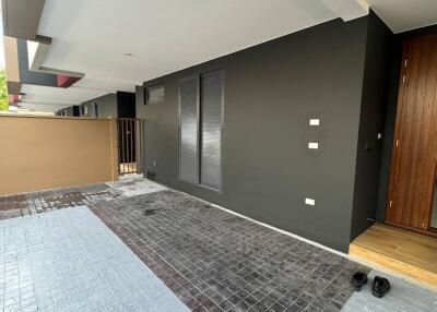 Covered outdoor area with tiled flooring and a wooden entrance door