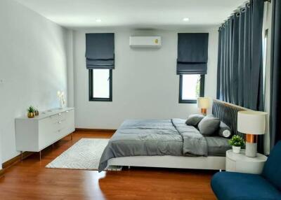 Modern bedroom with hardwood floors, large bed, dresser, and minimalist decor