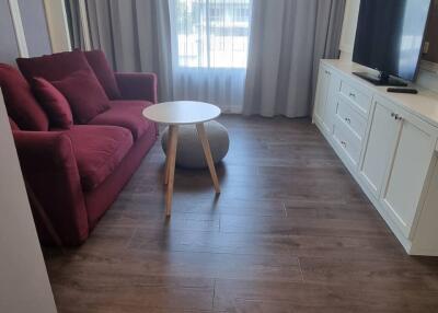 Modern living room with a red sofa, white coffee table, wall-mounted TV, and wooden flooring