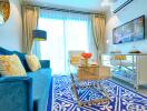 A well-furnished living room with a blue sofa, yellow cushions, a decorative rug, a glass coffee table, a TV, and elegant curtains.