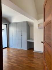 Bedroom with wooden flooring, built-in storage, and air conditioning