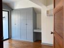 Bedroom with wooden flooring, built-in storage, and air conditioning