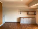 Living space with wooden flooring, built-in cabinets, and wall-mounted shelves