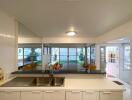 A modern kitchen with a sink, white cabinets, and view to a dining area and garden.