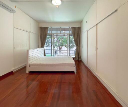 Spacious bedroom with a large window and wooden flooring