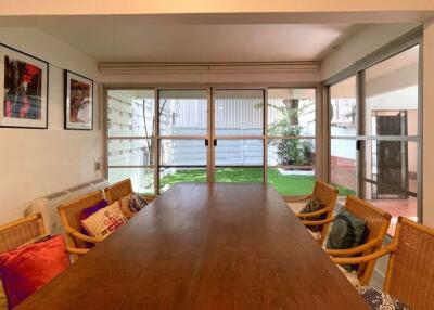 Spacious dining area with large table and chairs, adjacent to a garden