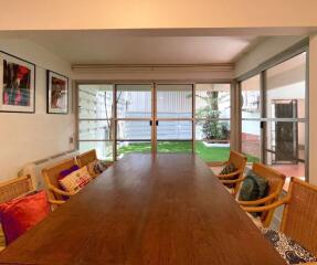 Spacious dining area with large table and chairs, adjacent to a garden