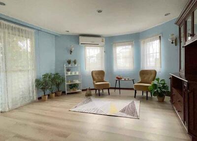 A cozy living room with blue walls, beige armchairs, and indoor plants