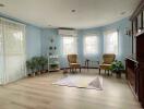 A cozy living room with blue walls, beige armchairs, and indoor plants