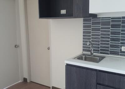 Modern kitchen with dark cabinets, white countertops, and tiled backsplash