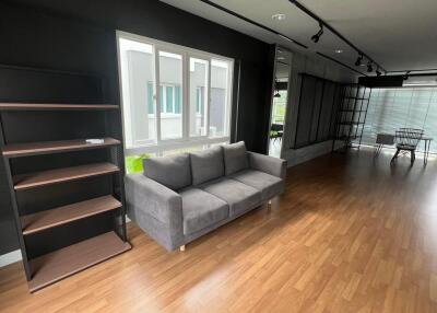 Modern living room with couch, bookshelves, and large windows