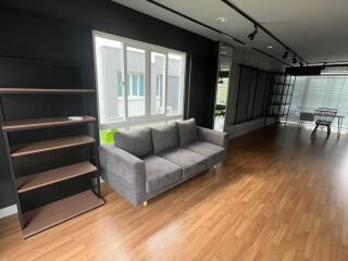 Modern living room with couch, bookshelves, and large windows