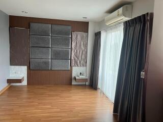 Modern living room with brown wooden flooring, large windows, and air conditioning unit