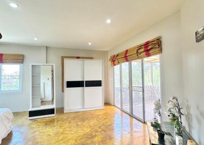 Spacious bedroom with hardwood floor and natural light