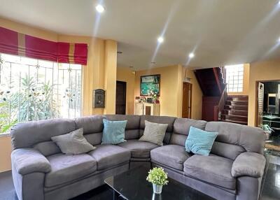 Cozy living room with large sofa, coffee table, and staircase in the background