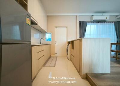 Modern kitchen with wooden cabinetry, stainless steel appliances, and adjacent dining area